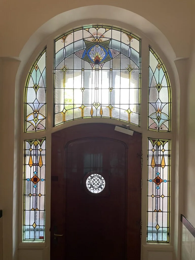 Houten voordeur met kleurrijk glas-in-loodraam in jugendstil-stijl aan de Oranje Nassaulaan.